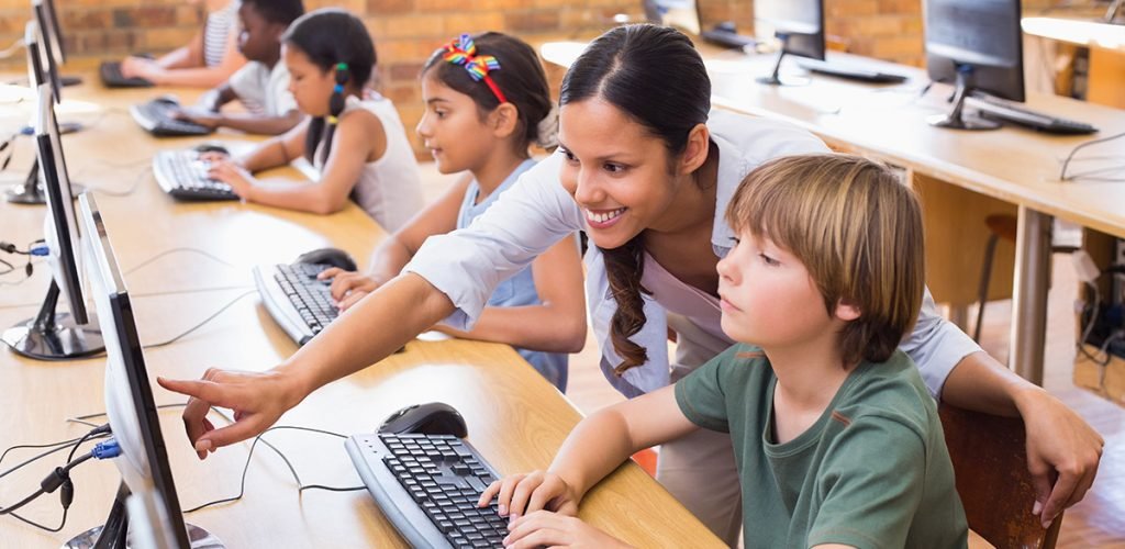 Cute pupils in computer class with teacher at the elementary school